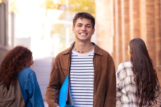 Attractive confident Caucasian teenage student looking at camera outdoors. Boy standing with happy face.