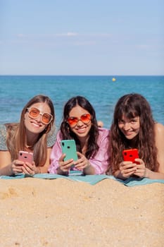 Group of smiling multiethnic women enjoying vacation. Beautiful and cheerful girls of generation z pose for a photo with a mobile phone.