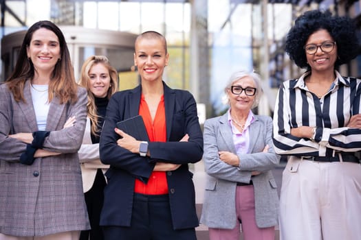 Five businesswomen standing side by side with their arms crossed looking at the camera smiling. Suitable for team, friendship and diversity concepts.