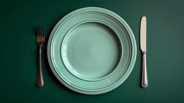 A simple, minimalist tabletop setting featuring a large, green, circular plate with a raised rim, and a fork and knife on either side. The background is a solid green, creating a clean and modern look.