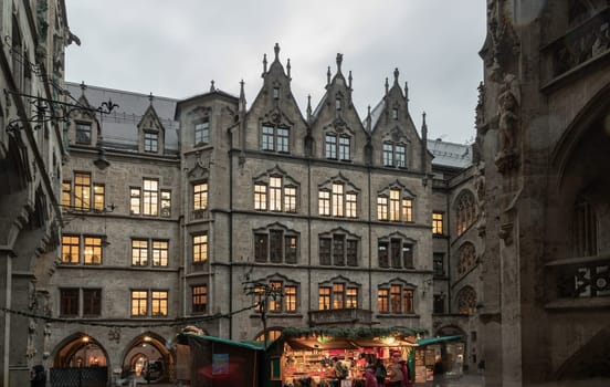 Munich, Germany - Dec 21, 2023 - The Festive illumination of A Christmas market held in courtyard of New Town Hall (Neue Rathaus) on Marienplatz square at Evening. Space for text, Selective focus.