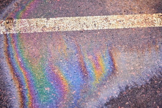 Oil spill on wet asphalt, parking lot with dividing lines. Highlighting environmental challenges related to water pollution