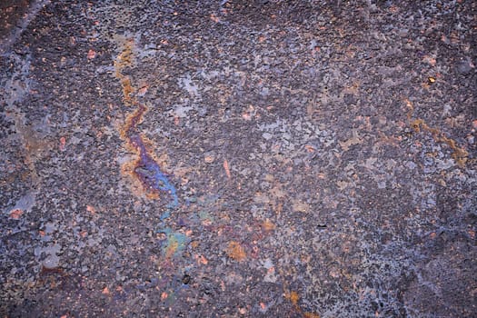 Petroleum fuel spilled on wet asphalt, abstract background.