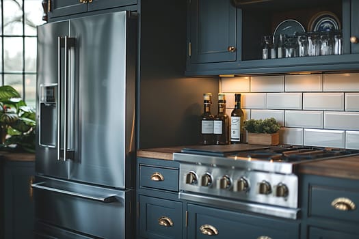 This is an image of a modern kitchen with stainless steel appliances. The kitchen features a stainless steel refrigerator with a bottom freezer drawer, a stainless steel stovetop, and a wooden countertop. There are three bottles of olive oil on the countertop, and a small plant in a wooden planter. The kitchen cabinets are painted a dark blue, and the backsplash is white subway tile. The kitchen is well-lit and appears to be a high-end, modern design.
