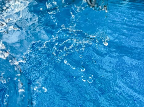 Background dynamic splash of clear water creating swirling wave in blue water with droplets suspended in motion. Clean water concept. High quality photo