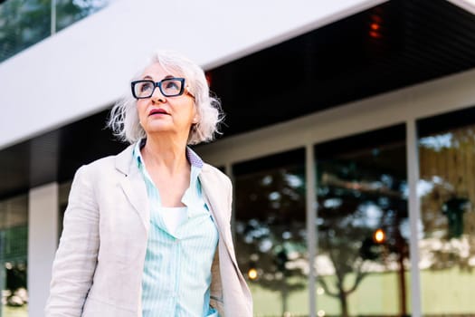 portrait of a stylish mature woman walking next to a building, concept of urban lifestyle in adulthood, copyspace for text