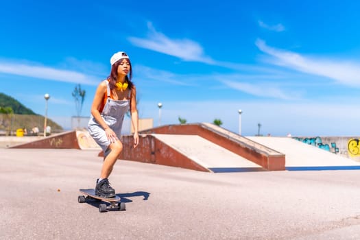 Full length photo of a young female cool asian skater practicing in an urban skateboard park