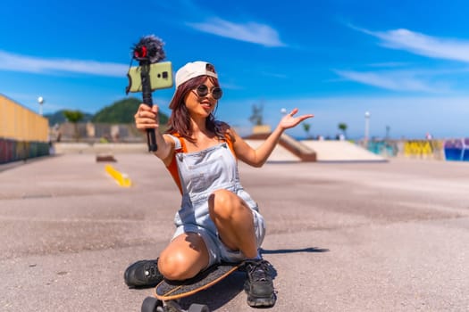 Chinese female young vlogger recording online video with mobile phone while skating in an urban park