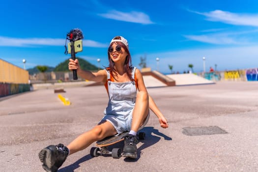 Smiling chinese female vlogger filming at skateboard park in summer