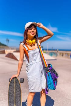 Vertical portrait of an asian chinese teenager with her skateboard at public park getting ready to skate