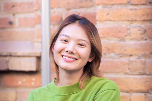 Attractive confident chinese teenage student looking at camera outdoors. Boy standing with happy face.