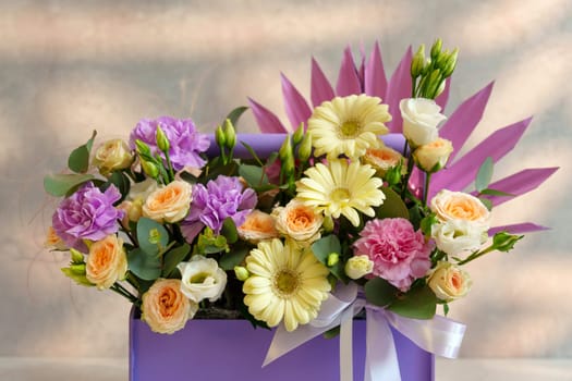 Bouquet of assorted flowers rests gracefully in a luxurious purple box, showcasing a blend of colors and textures.