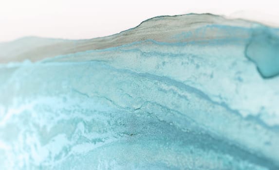 A close-up of a blue and white abstract painting, showcasing a serene wave-like pattern created by turquoise ink.