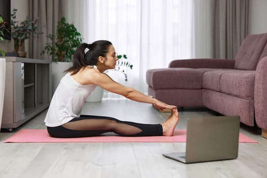 fit Caucasian woman worm up by stretching her body on pink exercise mat at home