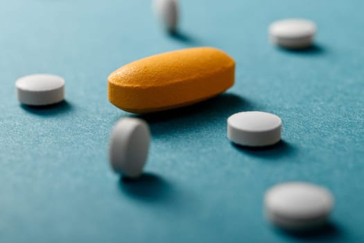 Close up of white and yellow pills on blue background.