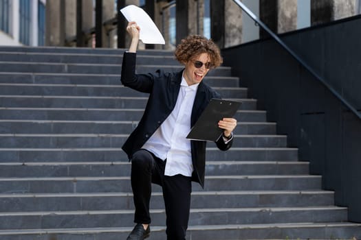 Successful happy Caucasian man businessman guy winner entrepreneur male leader boss throw papers documents outdoors near office building celebrating victory rejoice achievement great offer contract.