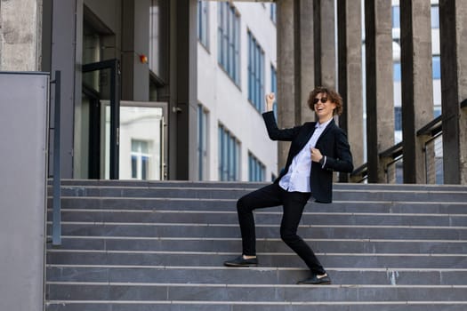 Dance, success or businessman in celebration at steps walking after a job interview, promotion or corporate deal. Excited, or happy dancing employee celebrates sales goals or target in downtown city.