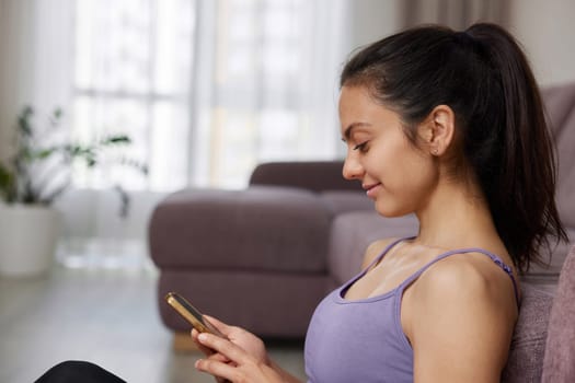 Happy sporty woman watching video online on smart phone at home