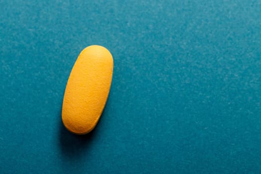 Top view of yellow pill or Dietary supplement on blue background, copy space.