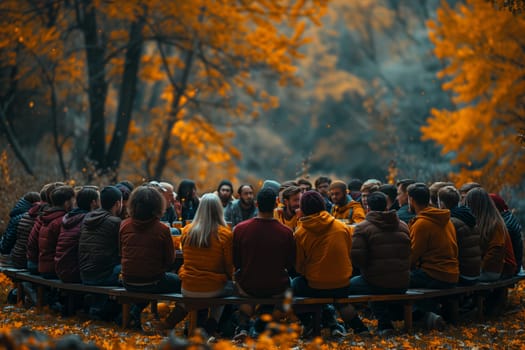 This image shows a group of friends gathered around a wooden table in a forest setting. The trees are in autumn colors, creating a beautiful backdrop. They are enjoying each others company and the beautiful weather. The image captures a moment of joy and friendship.