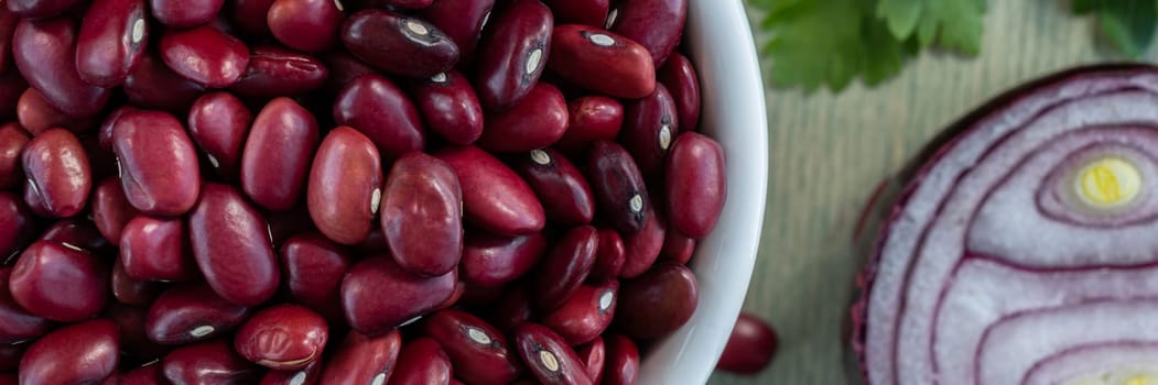 Banner of red beans in white plate with onion and parsley. close up red beans with spices on a green wooden background. Flat lay. Top view