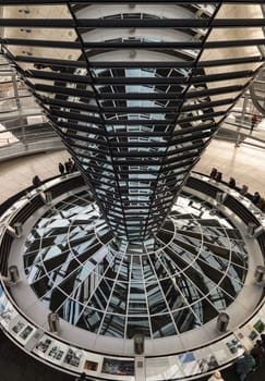 Berlin, Germany - Dec 20, 2023 - Several tourists visitor inside the futuristic glass dome of Reichstag building. Contemporary architecture of the Cupola of the Reichstag dome, a major tourist attraction of the berlin city, Space for text, Selective focus.
