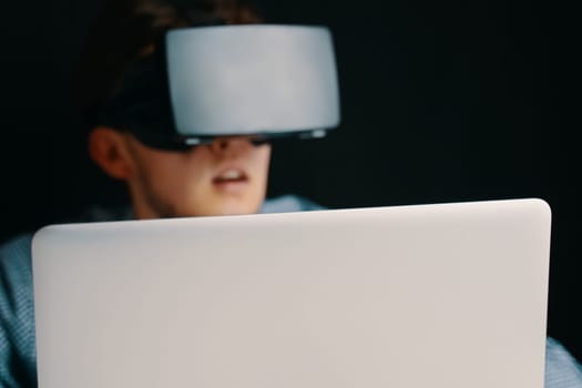 A young person in a VR headset with a laptop, symbolizing advanced technology and immersive digital experiences