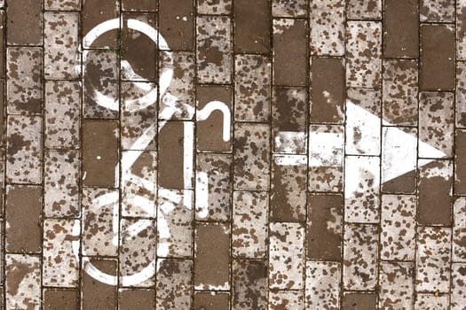 A monochrome photograph featuring a brown brick wall adorned with a blackandwhite bicycle and arrow painted in an urban design font