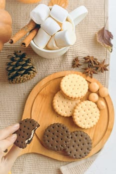 Delicious assortment of cookies and marshmallows on a wooden board, perfect for autumnal treat vibes.