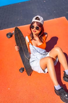 Vertical top view of a young chinese woman sitting on a colorful skateboard park