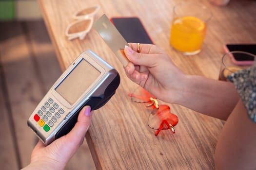 Unrecognizable Hand of a young woman holding a credit card and making a payment transaction.