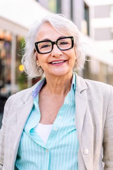 portrait of a stylish mature woman smiling happy looking at camera outdoors, concept of urban lifestyle in adulthood