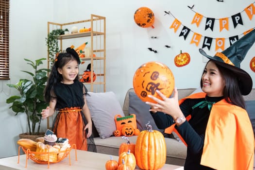 A joyful mother and daughter enjoying Halloween festivities at home, surrounded by festive decorations and wearing themed costumes.