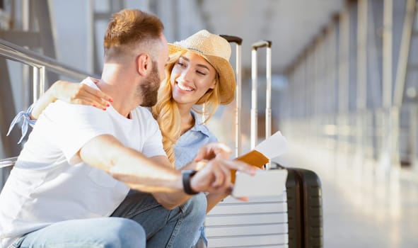 Loving couple in airport using travel app on smartphone, waiting for departure, panorama with copy space
