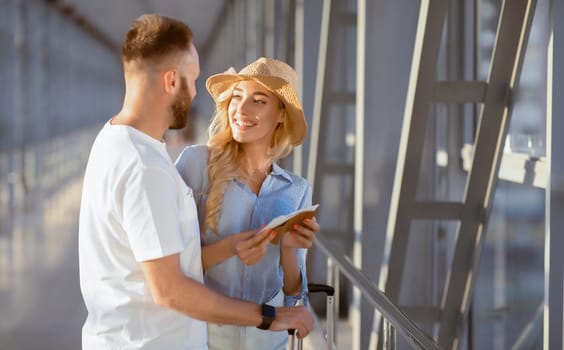 Traveling Concept. Portrait of lovely couple looking at each other standing in terminal and holding tickets