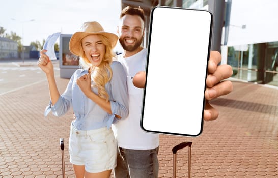 Ready For Vacation. Excited spouses with suitcases showing boarding passes and passports, standing near airport