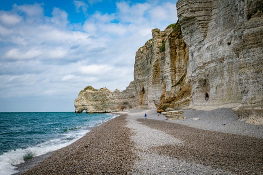 etretat,france,23-04-2024, woman walking on the beach at the famous calck cliffs in normandy france near etretat, view from the beach