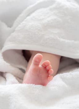 A touching display of a baby's foot, barely visible as it peeks from beneath the veil of a pure white towel
