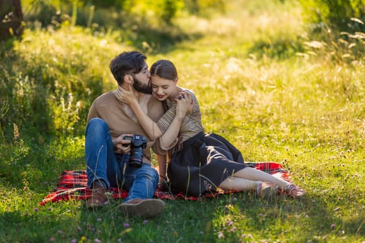 young couple sits in nature and looks at the camera at the resulting picture