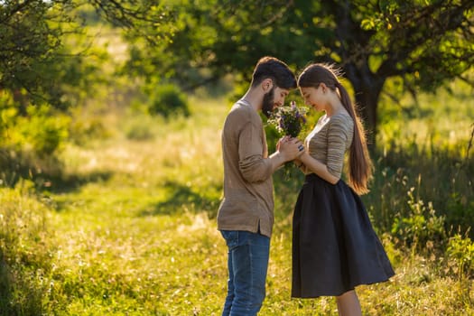 couple in nature with wildflowers, smelling a bouquet