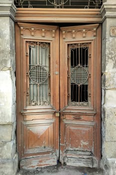 old entrance wooden double-leaf brown door with wrought iron decor and glass.