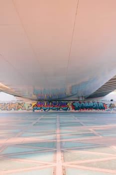 Vibrant graffiti artwork adorns the walls beneath a bridge in Valencia. The colorful murals contrast with the urban structure, adding an artistic touch to the city landscape.