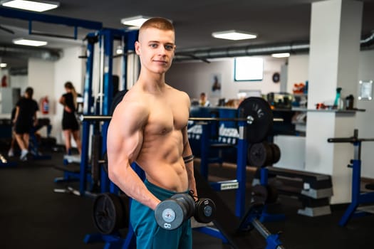 Professional bodybuilder lifting dumbbells in a gym.