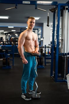 Young fitness trainer holding a barbell standing in the gym.