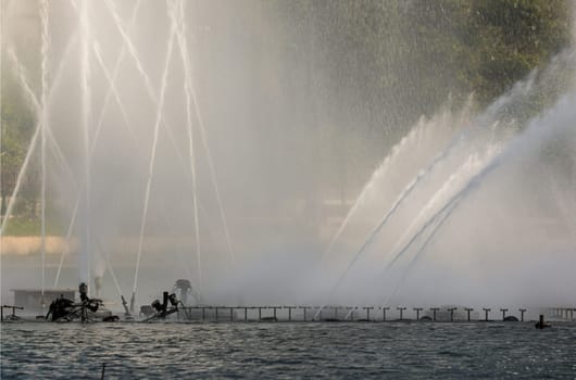 An Impressive Ornamental Water Fountain in a Large Pond. Water drops splashing on water surface, Space for text, Selective focus.