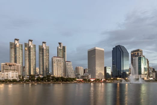 Bangkok, Thailand - 22 Jun, 2024 - Picturesque view of skyscrapers and dramatic sky before sunset. Cityscape office buildings with modern architecture with reflection on the surface of water, Copy space, Selective focus.
