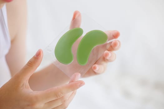 a girl applies moisturizing patches with vitamins under her eyes, a modern cosmetic product for the eyes to smooth out fine wrinkles and remove redness