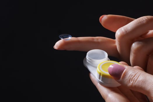 woman puts on contact lenses for vision close-up on a dark background, macro photo of contact lenses, astigmatic eyes, colored lenses