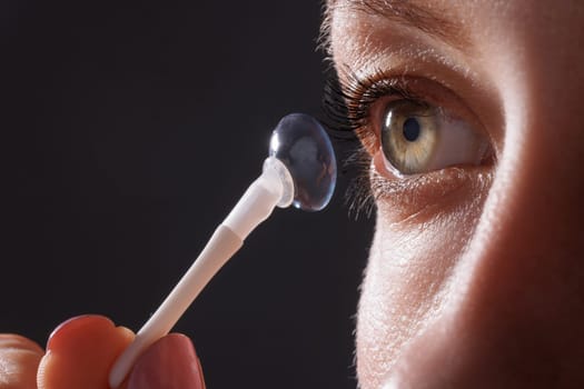 woman puts on contact lenses for vision close-up on a dark background, macro photo of contact lenses, astigmatic eyes, colored lenses