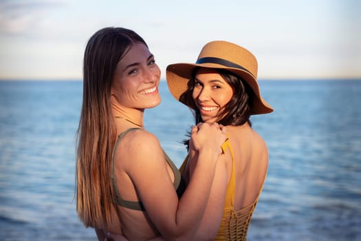Cheerful multiethnic friends with sunglasses happy on vacation on the beach, looking at the camera.